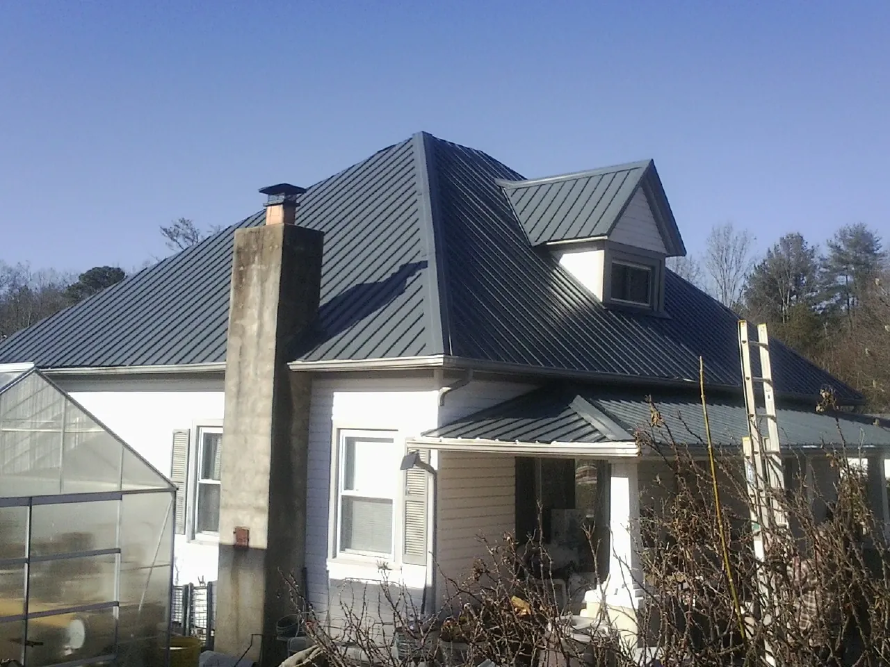 Dark blue standing seam metal roof on a white farmhouse with dormer — Slate & Tile Roof Repair by Roofing Brothers in Manchester Township