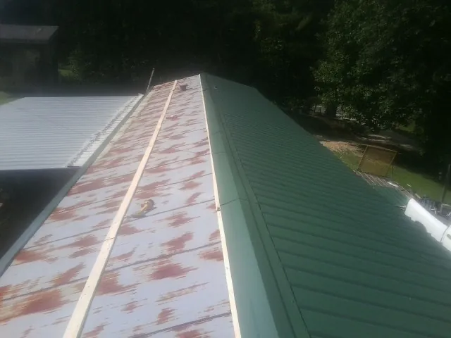 Old rusted panels beside newly installed green metal roofing — Wind Damage Roof Repair by Roofing Brothers in Manchester Township
