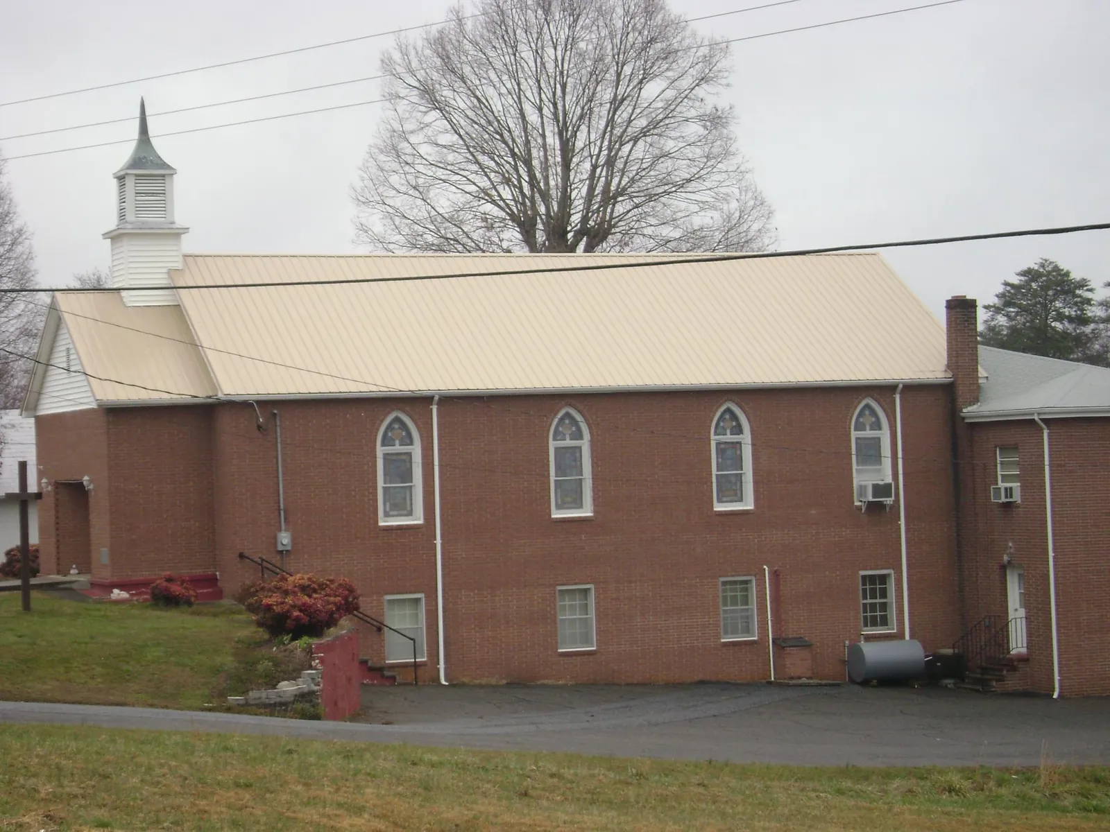 New tan metal roof on a brick church with a white steeple in Manchester Township