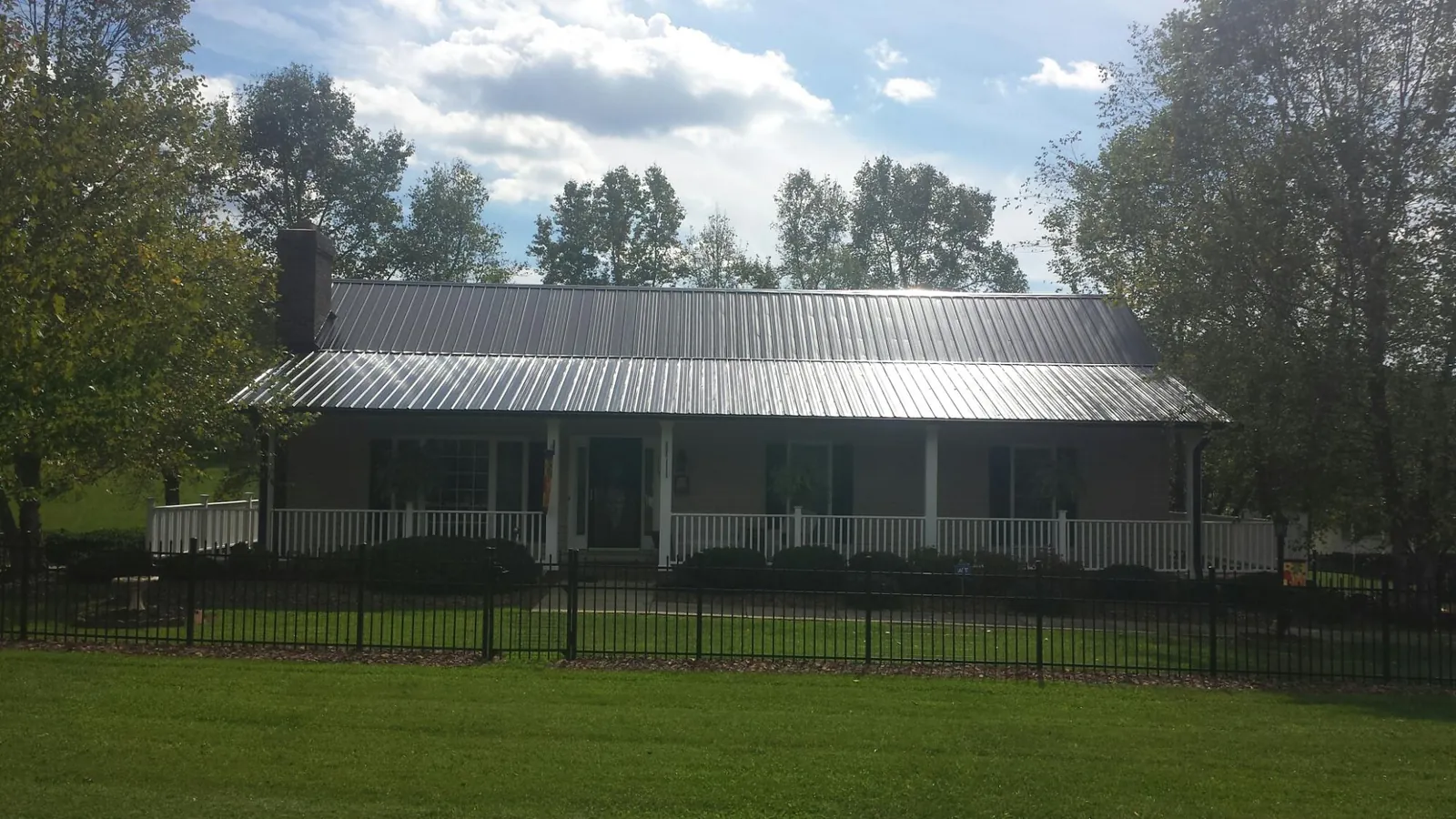 Gray metal roof on a brick ranch with a full width front porch — Gutter Guard Installation work by our crew in Manchester Township