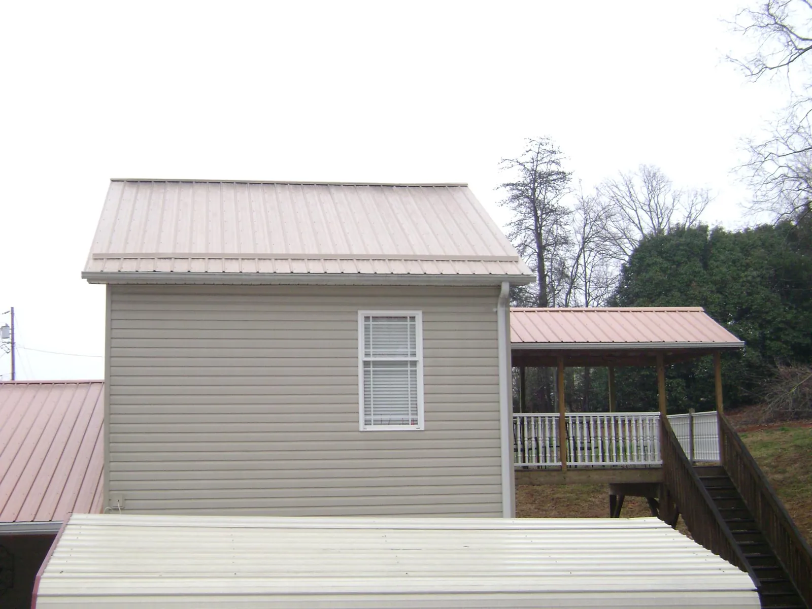 Tan metal roofs on a two story addition and attached porch, from a Roof Replacement job in Manchester Township