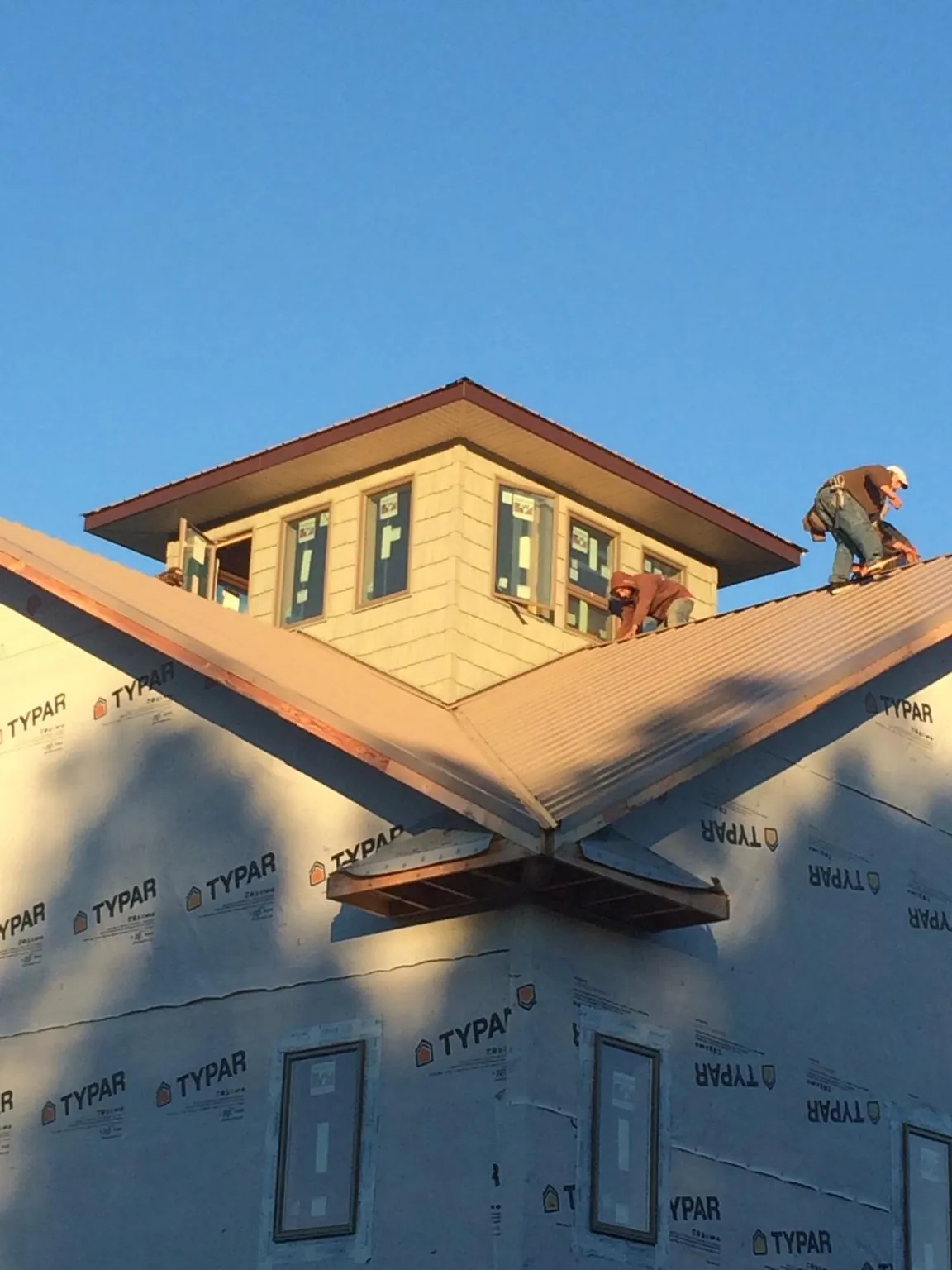 Roofers working around a rooftop cupola on a new metal roof at sunset — Roof Waterproofing in Manchester Township by Roofing Brothers